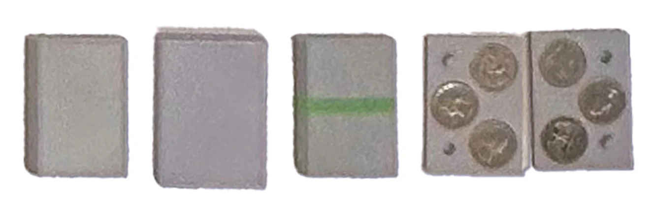 Grey 3D-printed battery housings, one wrapped in green, beside a coin-cell holder