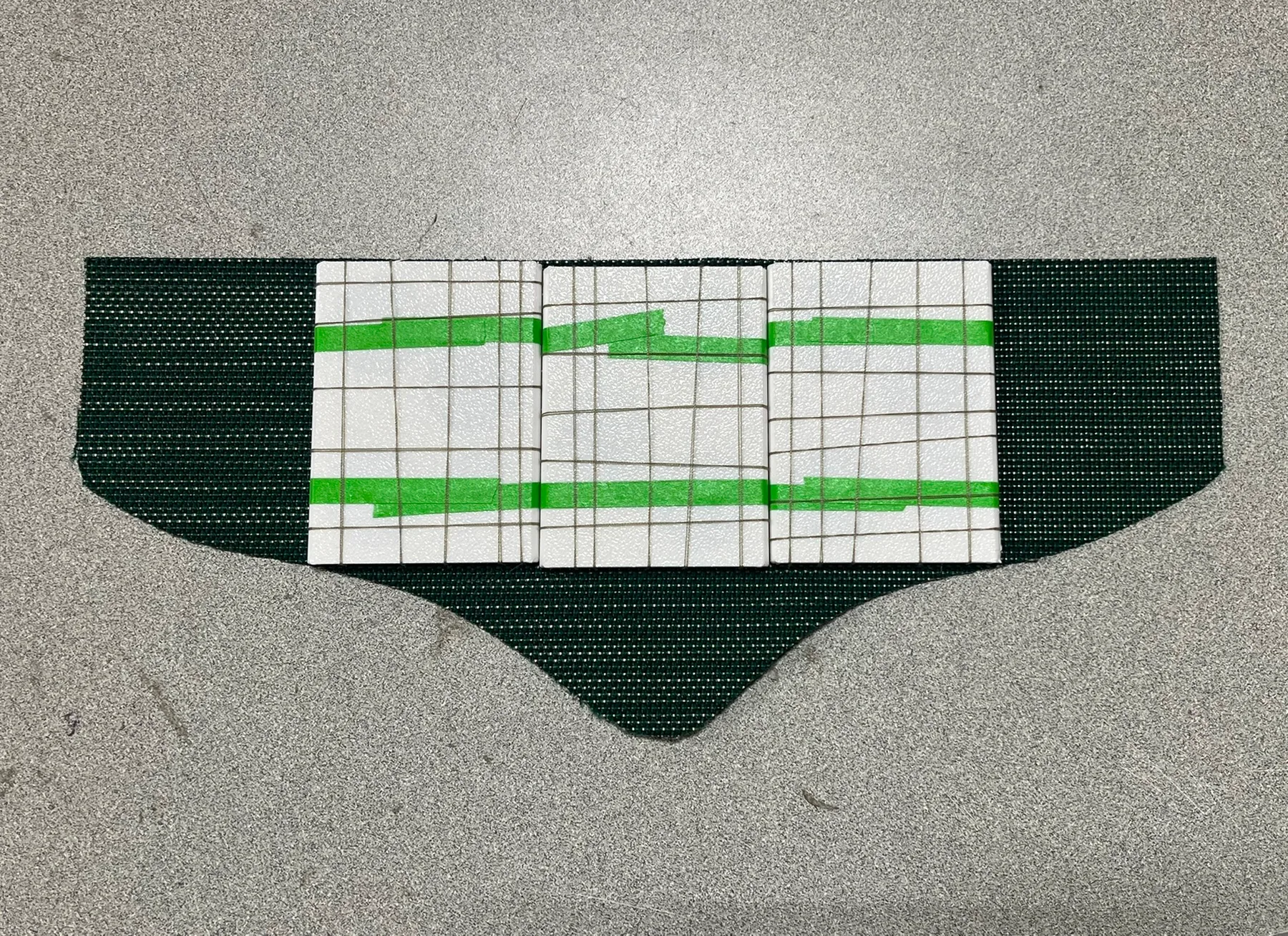 Green knit belt panel with white tape marking the heater layout