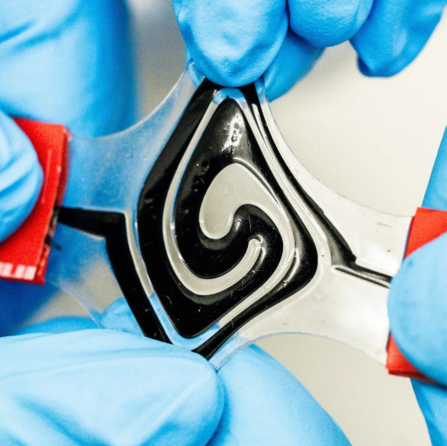 A flexible battery being stretched by gloved hands