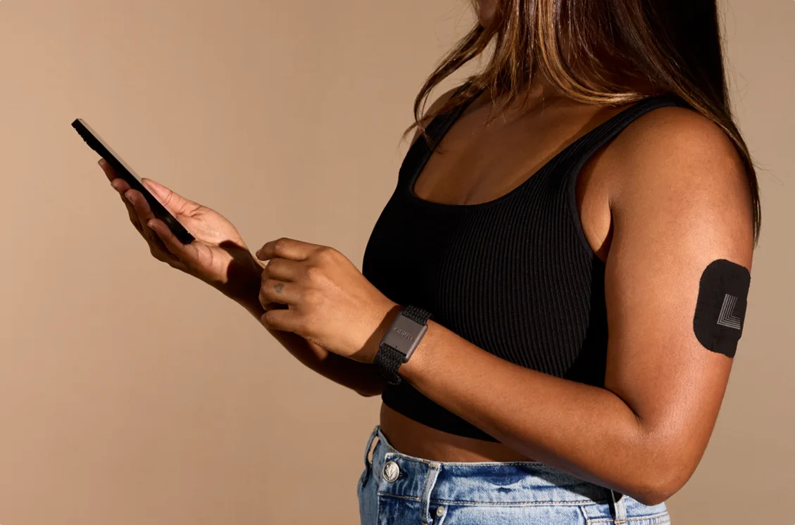 A woman checking her phone while wearing the Limbo band and sensor
