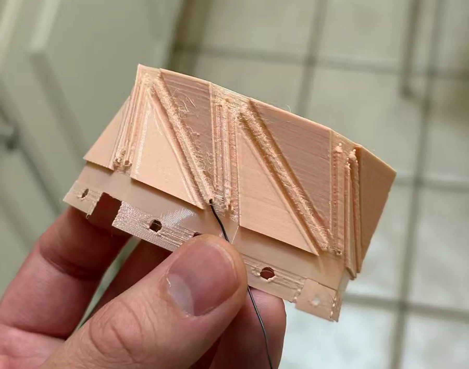 A hand holding a 3D-printed folding rim in pink TPU