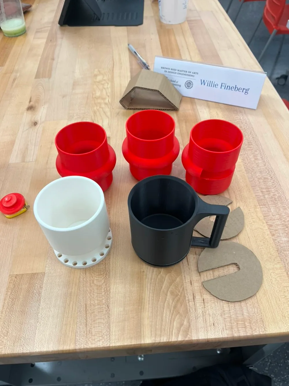 Printed mug studies in red, white and black on a workbench