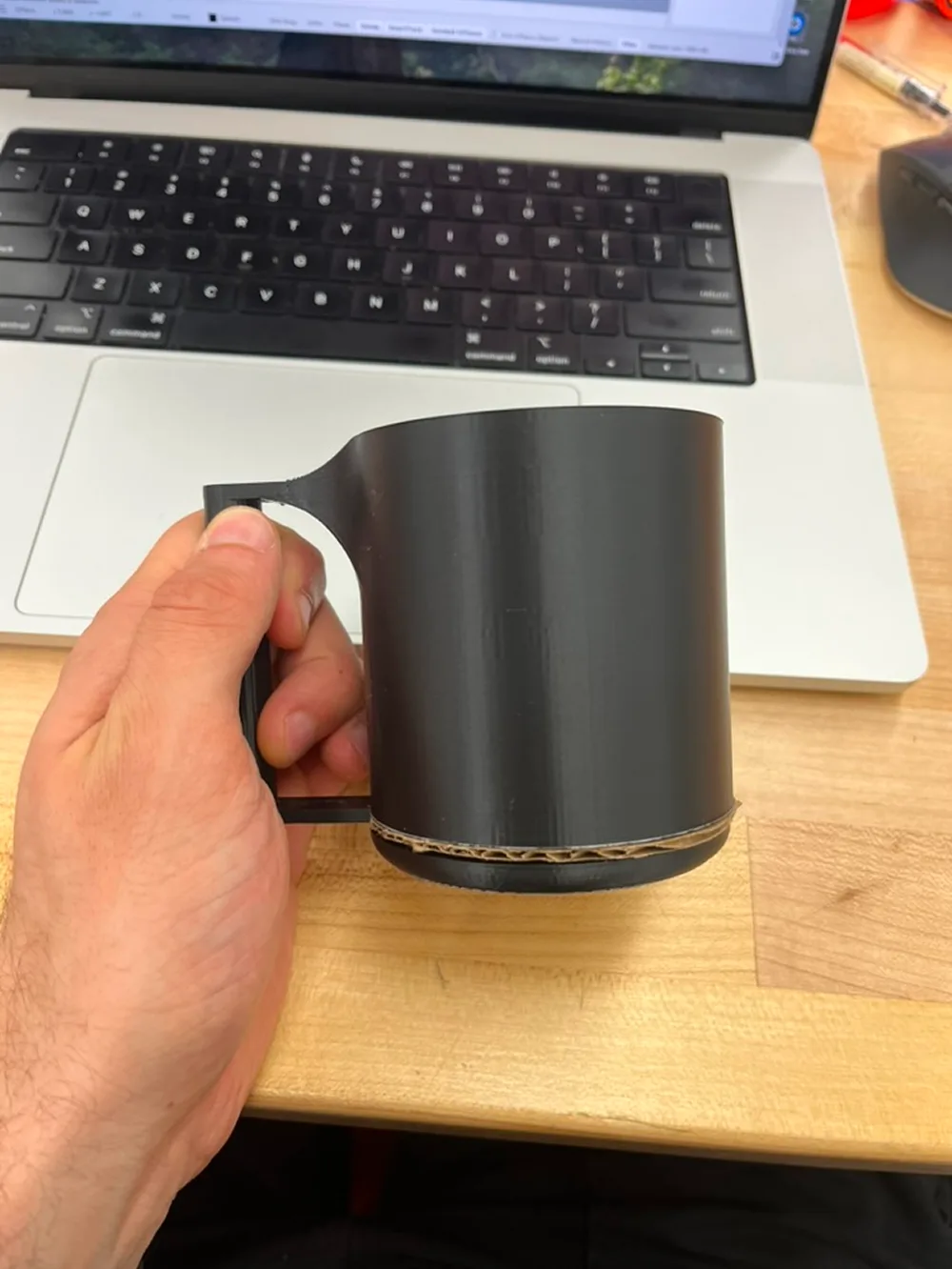 A hand holding a black printed mug with a slim handle