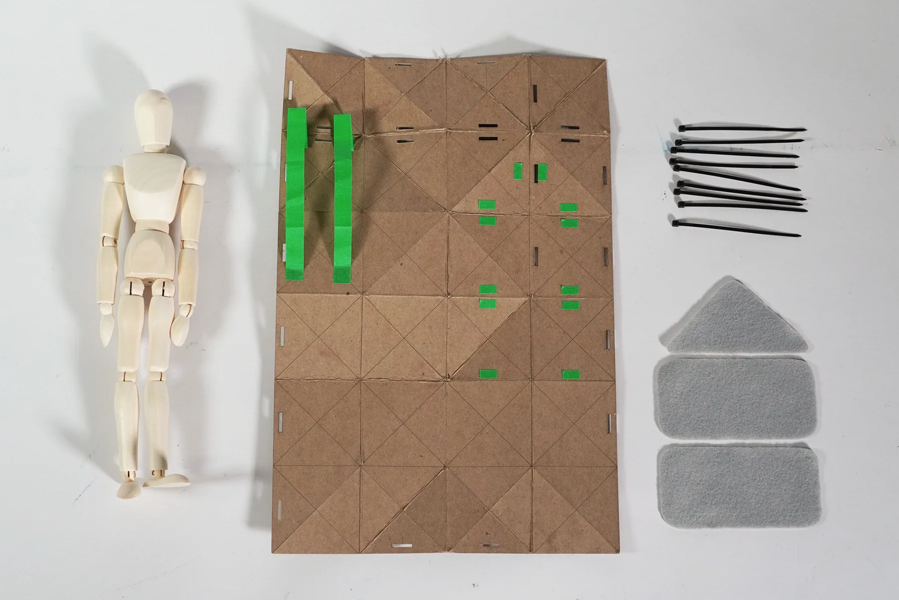 The flat shelter sheet laid out beside a scale figure, webbing, rods and pads